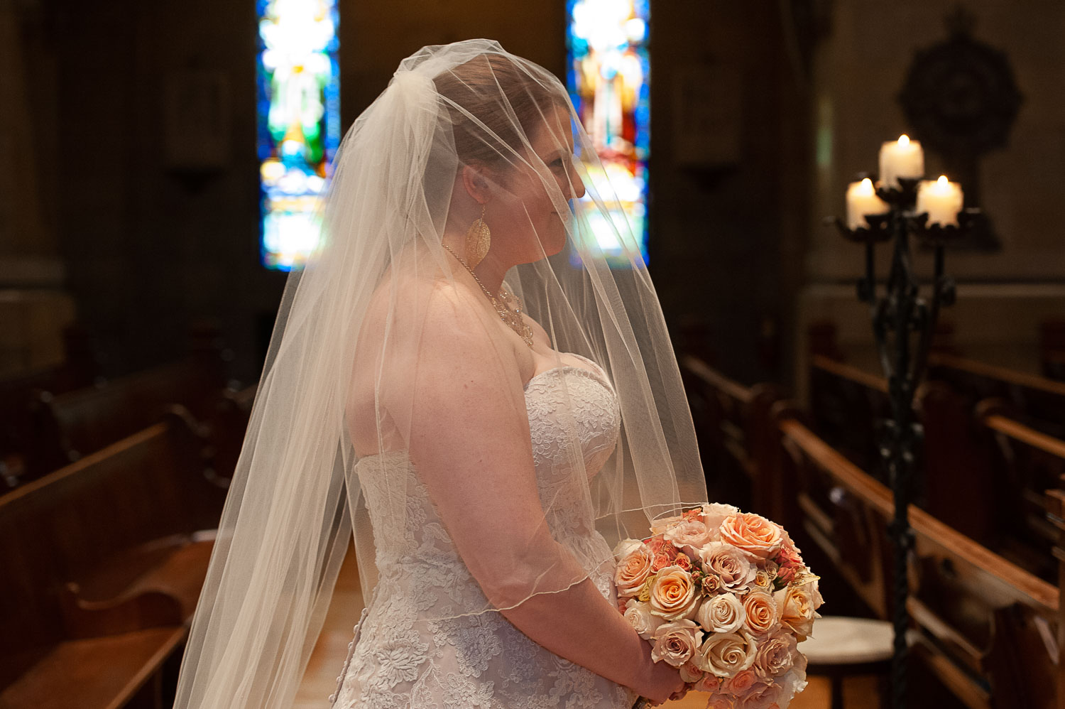 bride with a veil holding a bouquet of roses at The Basilica of Saint Mary