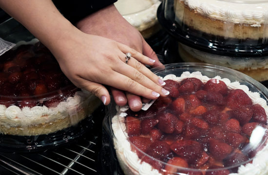 Bride and groom showing off their engagement ring over a strawberry cheesecake at Costco
