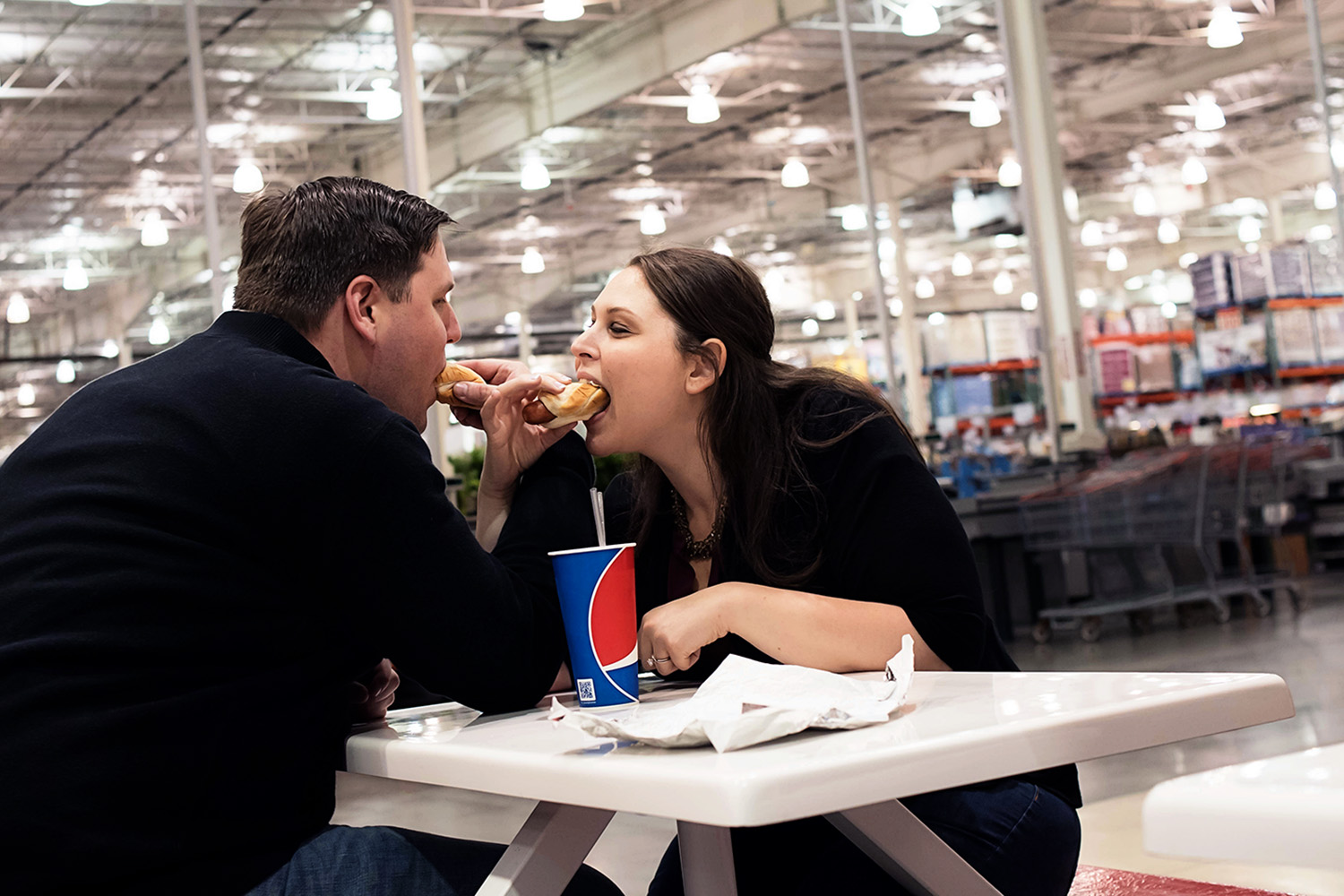 Engagement session at Costco with the couple sharing a hotdog