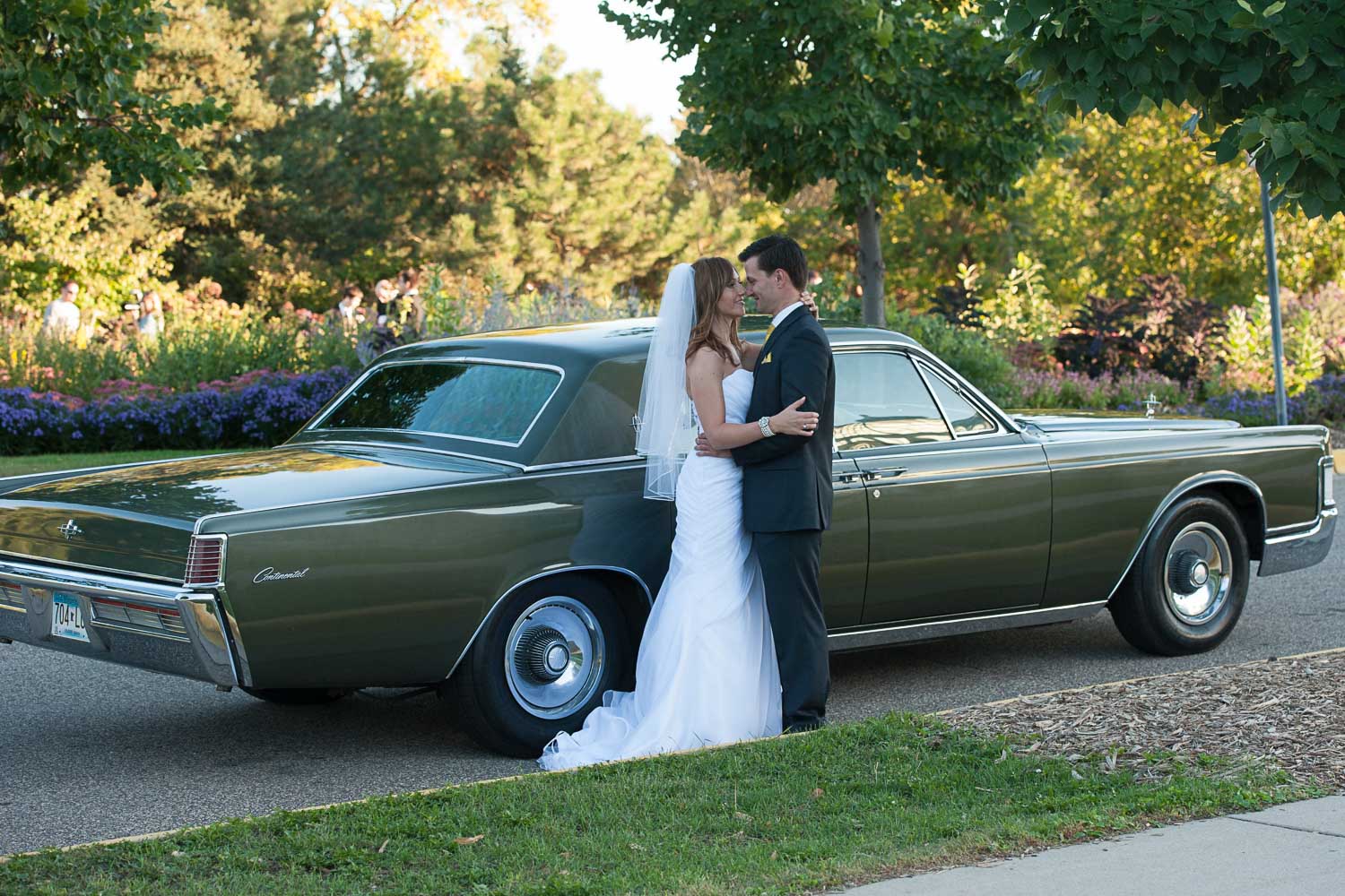 bride and groom next to a classic car