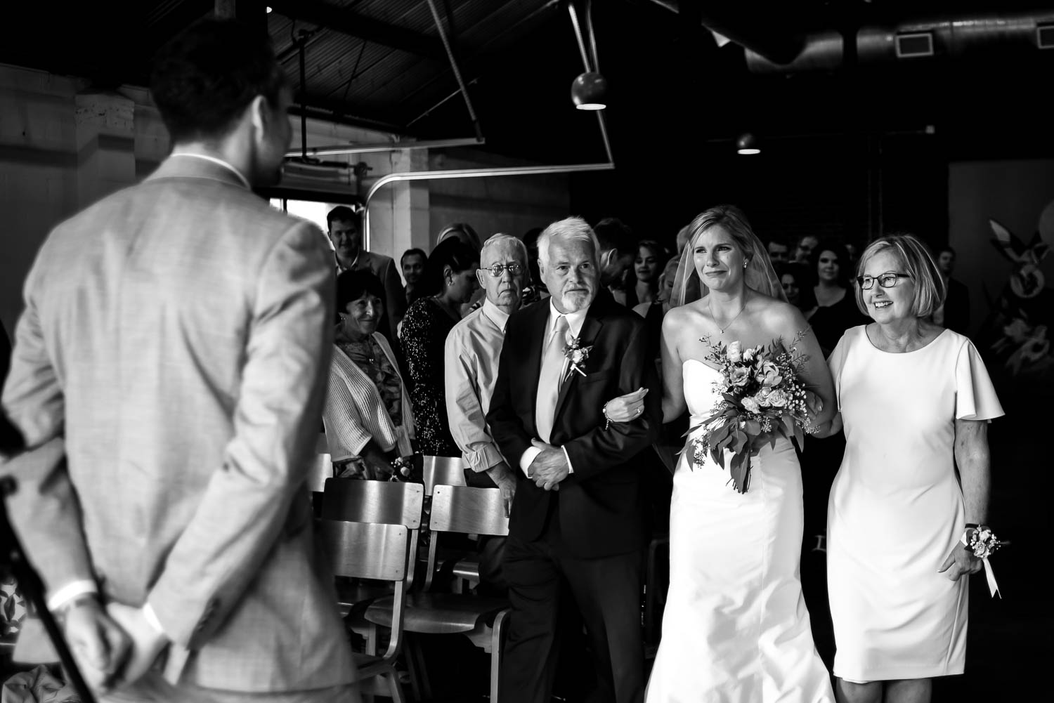groom watching bride walk down the aisle with her parents at Paikka