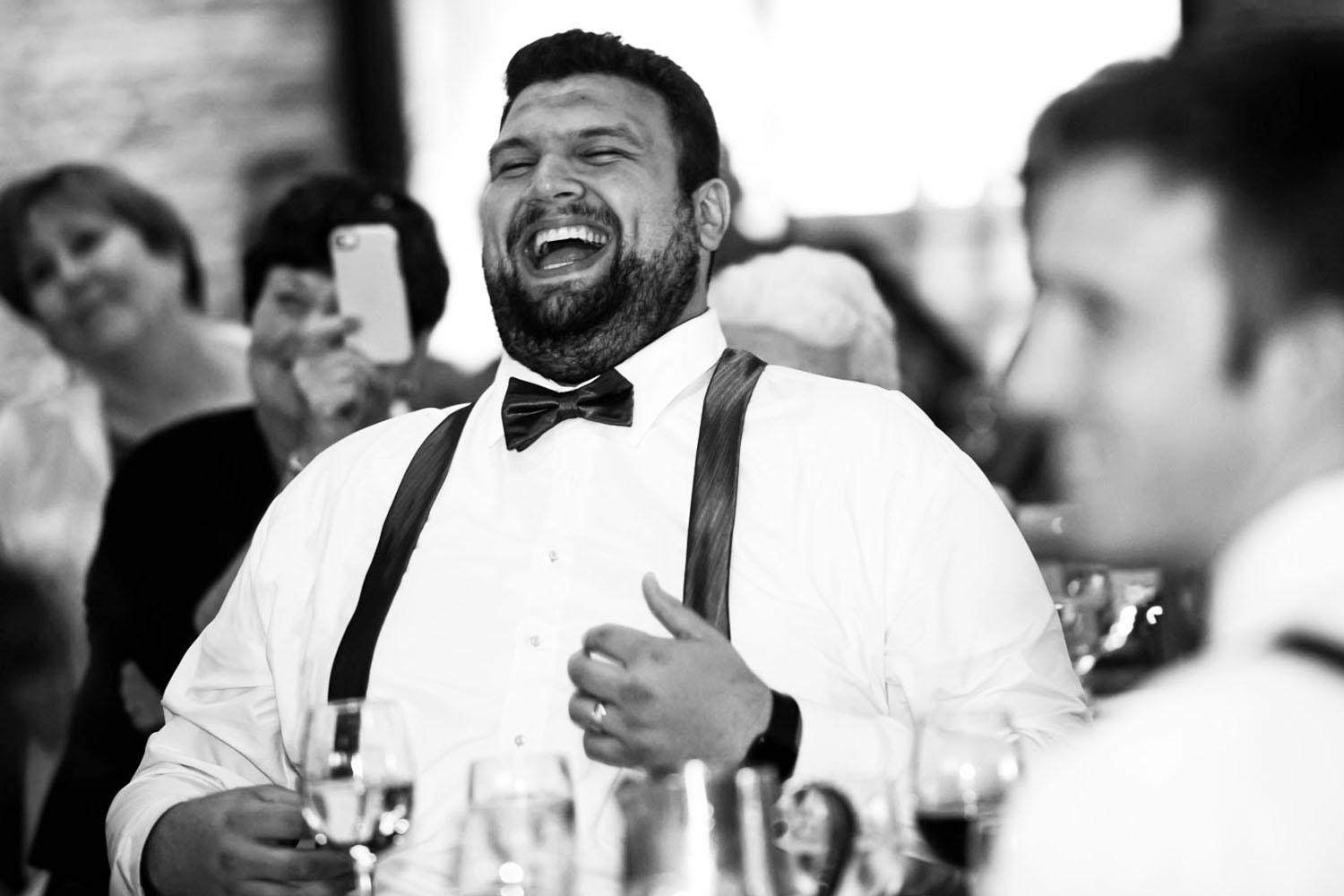 groomsman laughing during speeches at wedding
