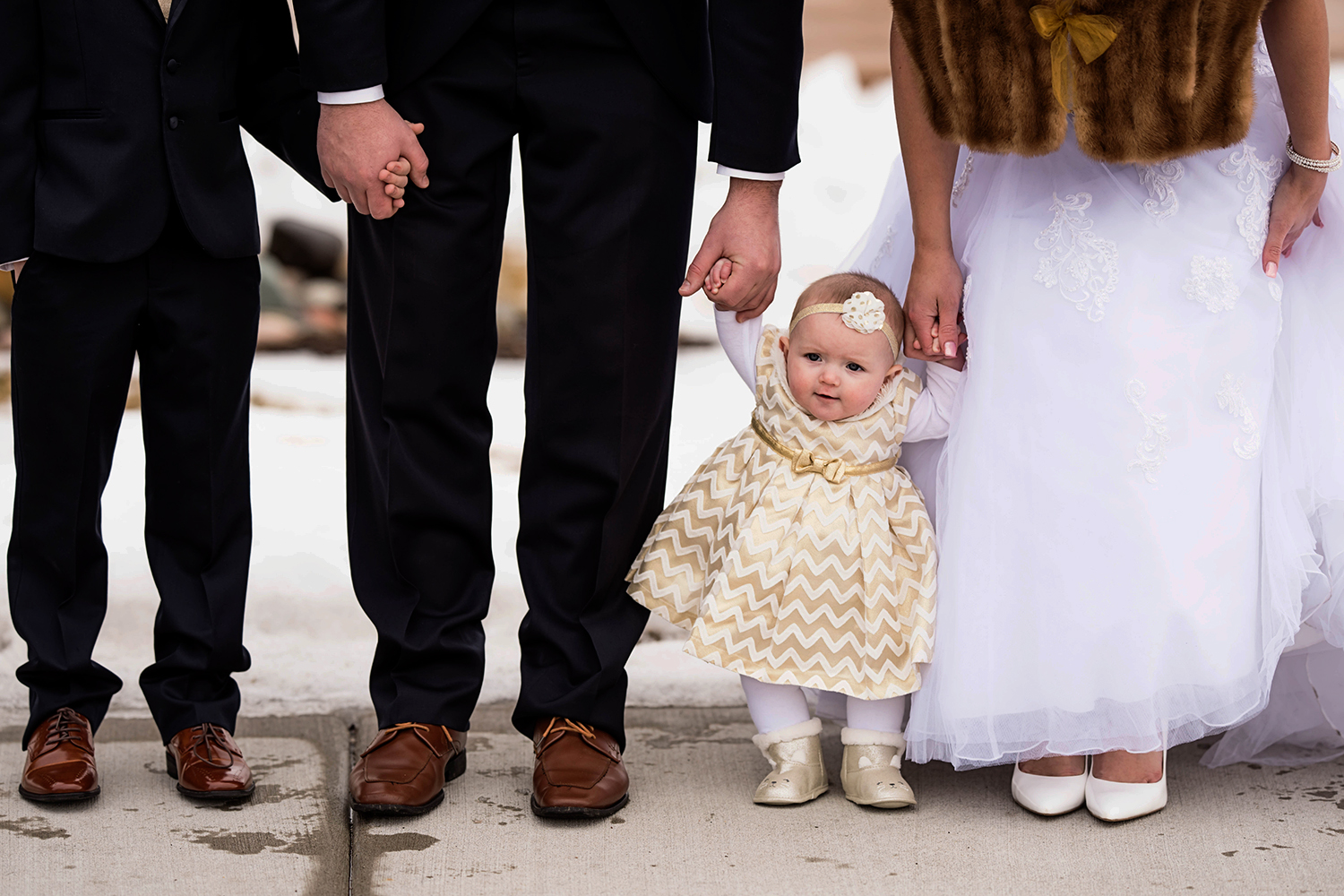 bride and groom holding hands with the baby flower girl