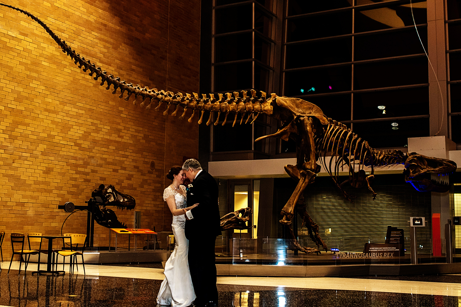bride and groom at the science museum in front of the trex 