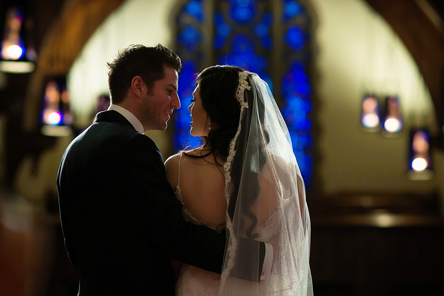 bride and groom in front of a stained glass window