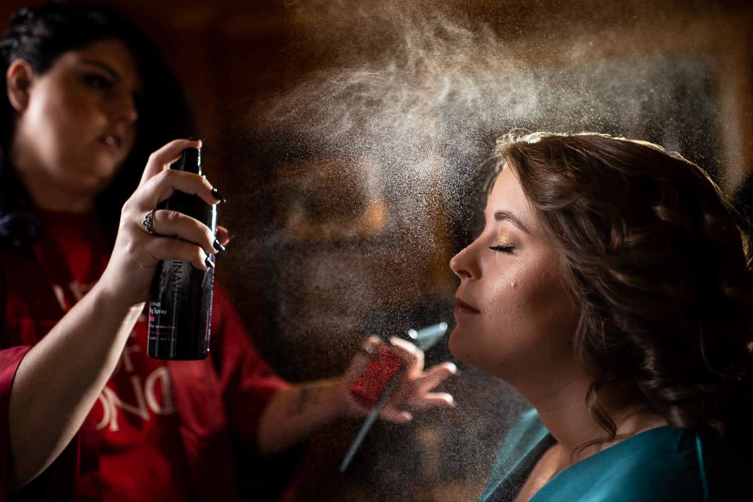 Bride getting her hairs sprayed while getting ready