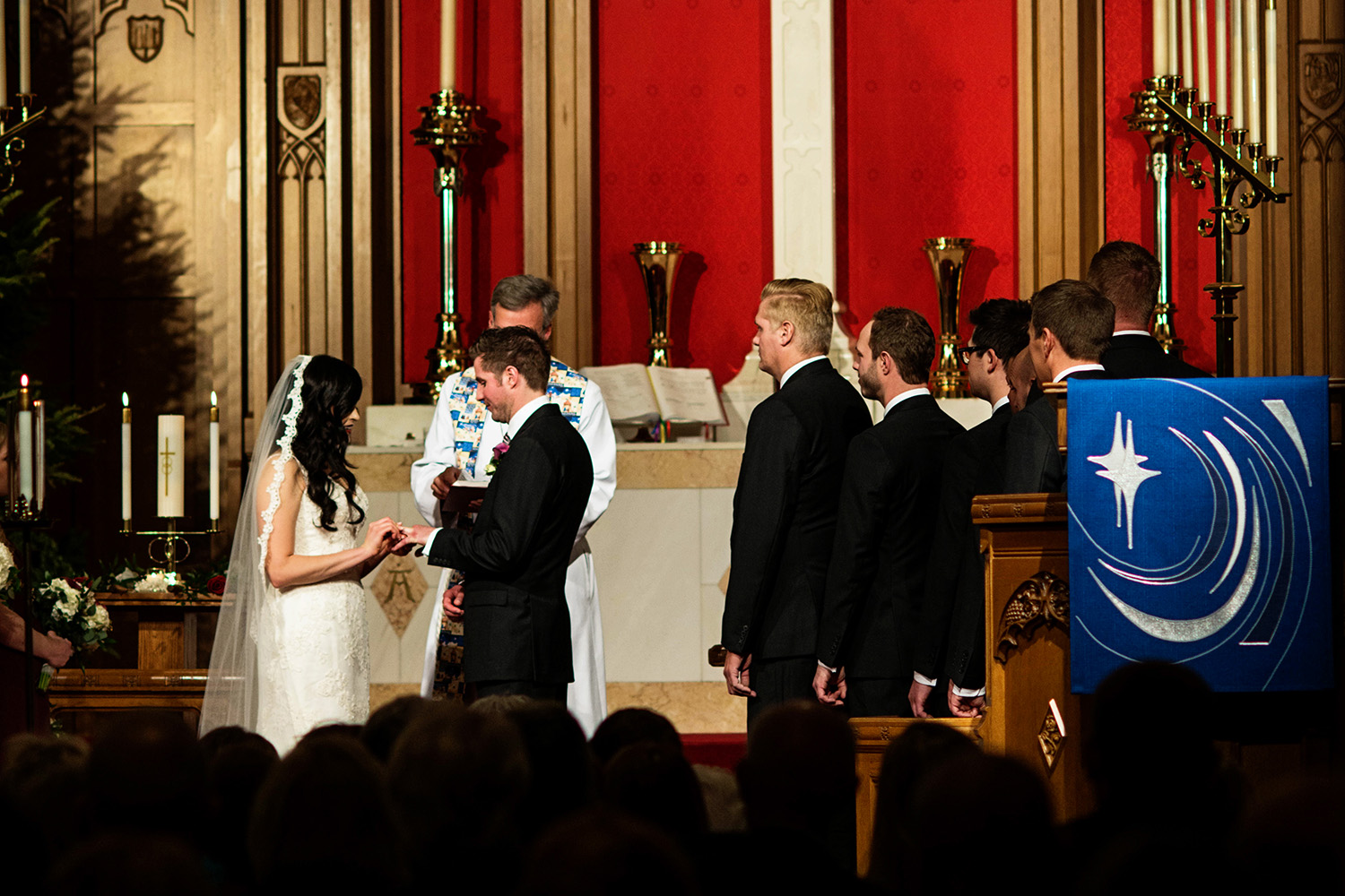 bride putting the groom's ring on during the wedding ceremony in Minneapolis at Mount Olivet Lutheran Church