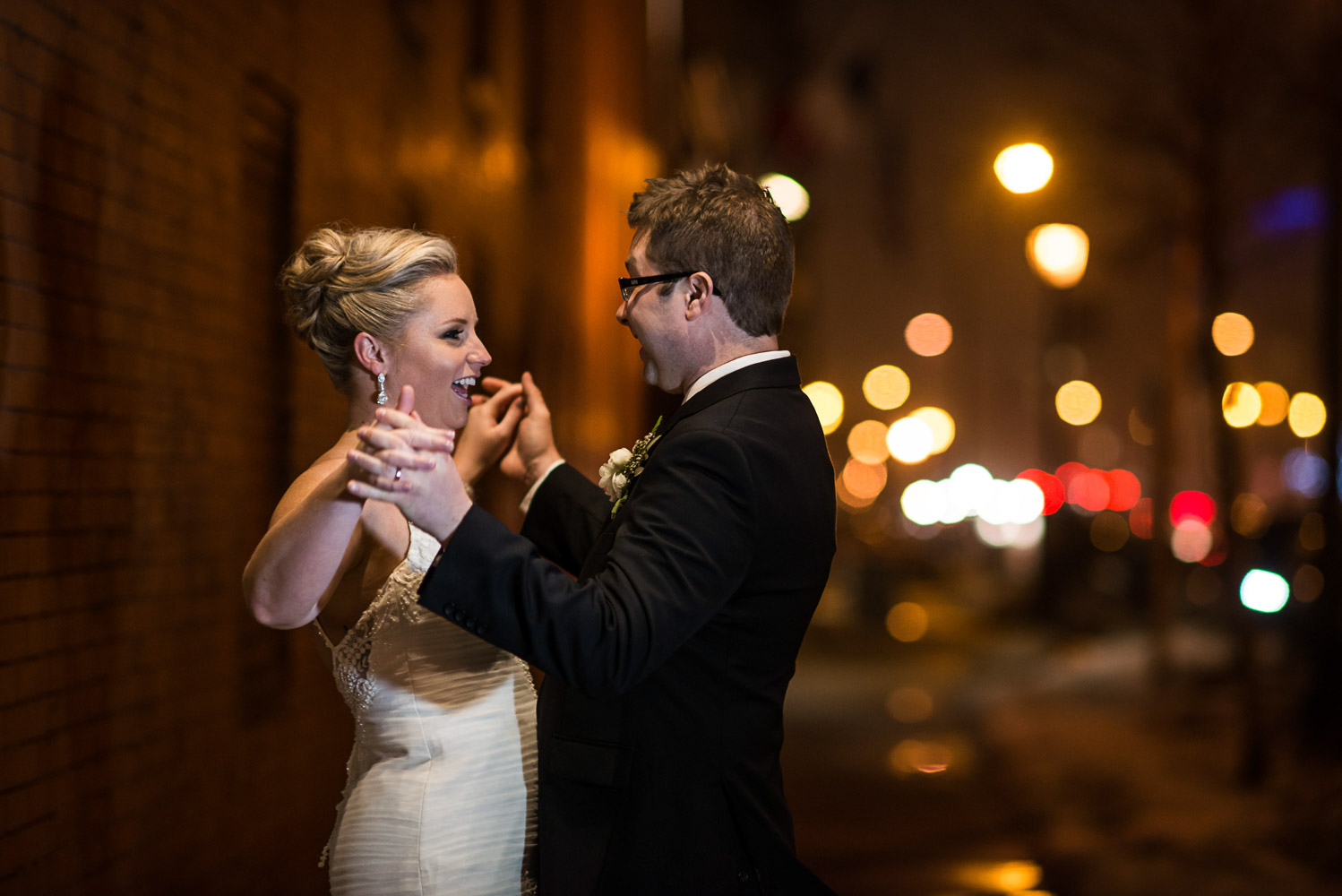 bride and groom holding hands outside of Aria in Minneapolis with the city lights in the background