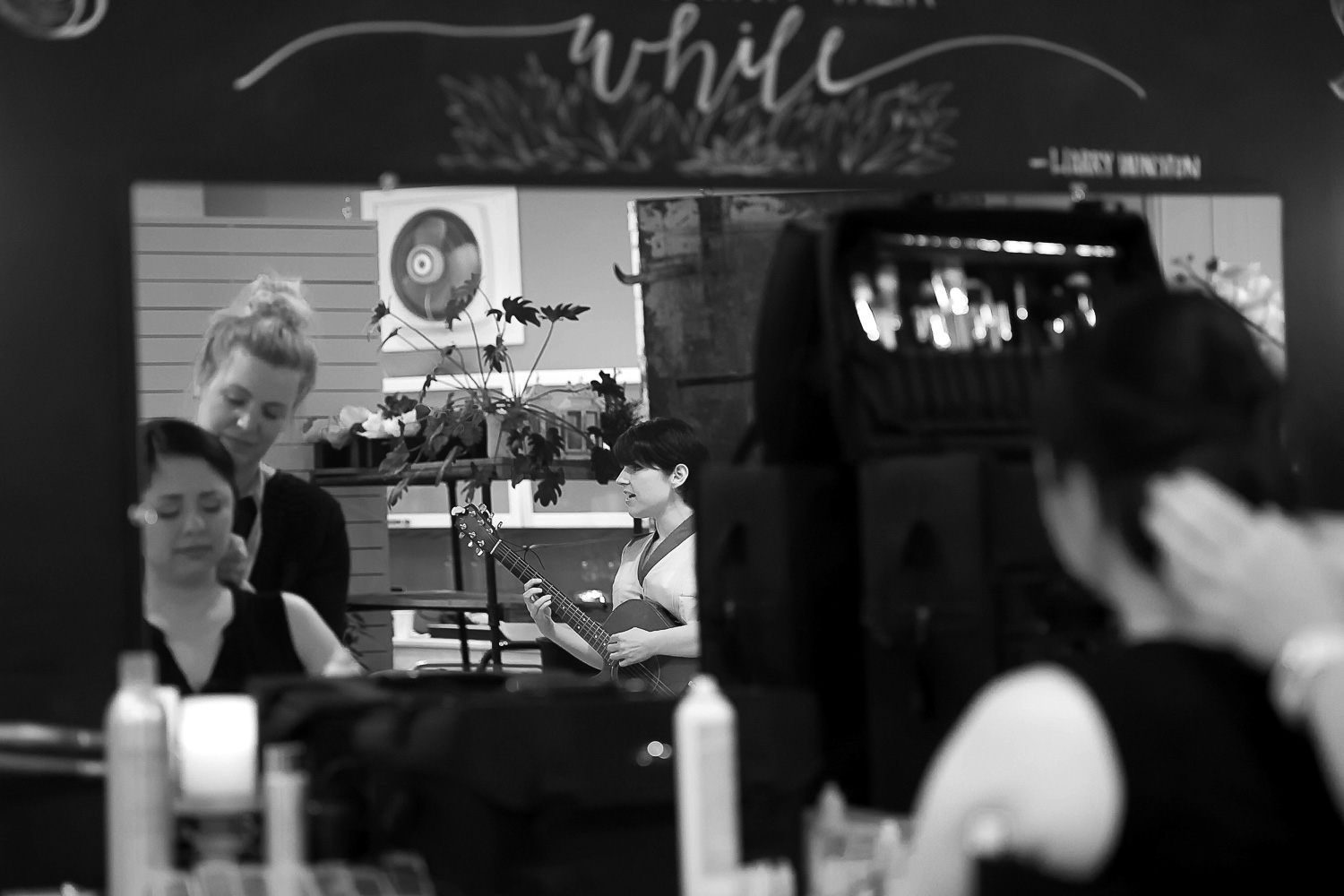 bride playing a song on the guitar for her bride while getting her hair and makeup done before her wedding in Minneapolis at Neu Neu
