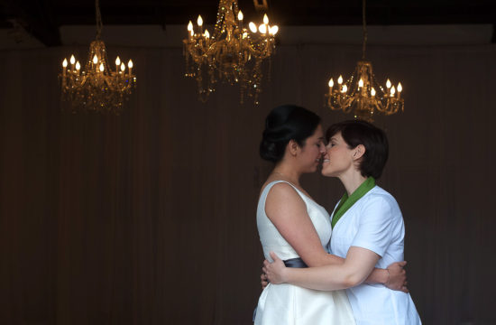 same sex couple kissing with chandeliers in the background at their venue Neu Neu n Minneapolis
