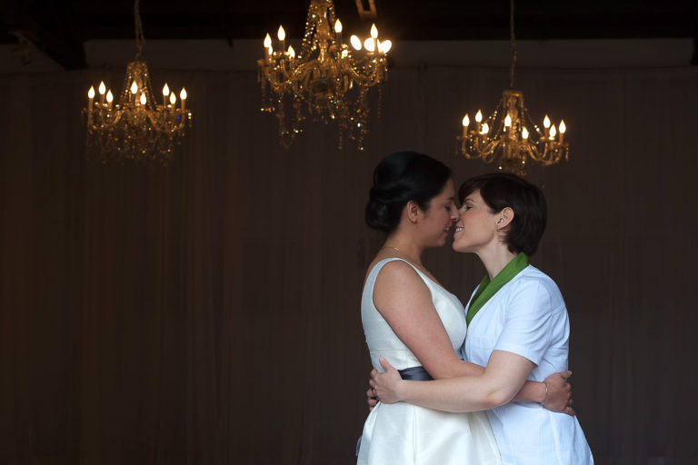 same sex couple kissing with chandeliers in the background at their venue Neu Neu n Minneapolis