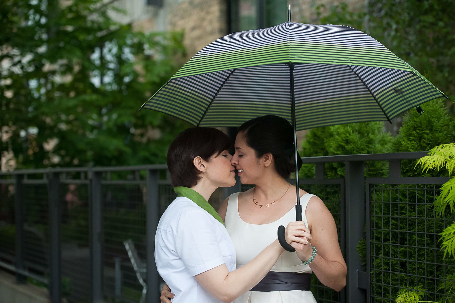 same sex couple kissing under a green umbrella in Minneapolis