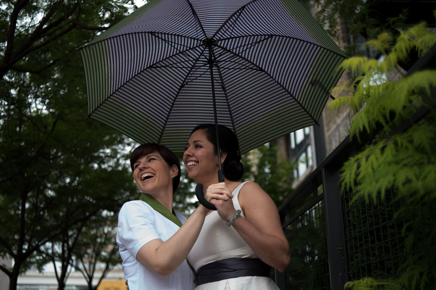gay couple holding a green umbrella in the rain on their wedding day in Minneapolis