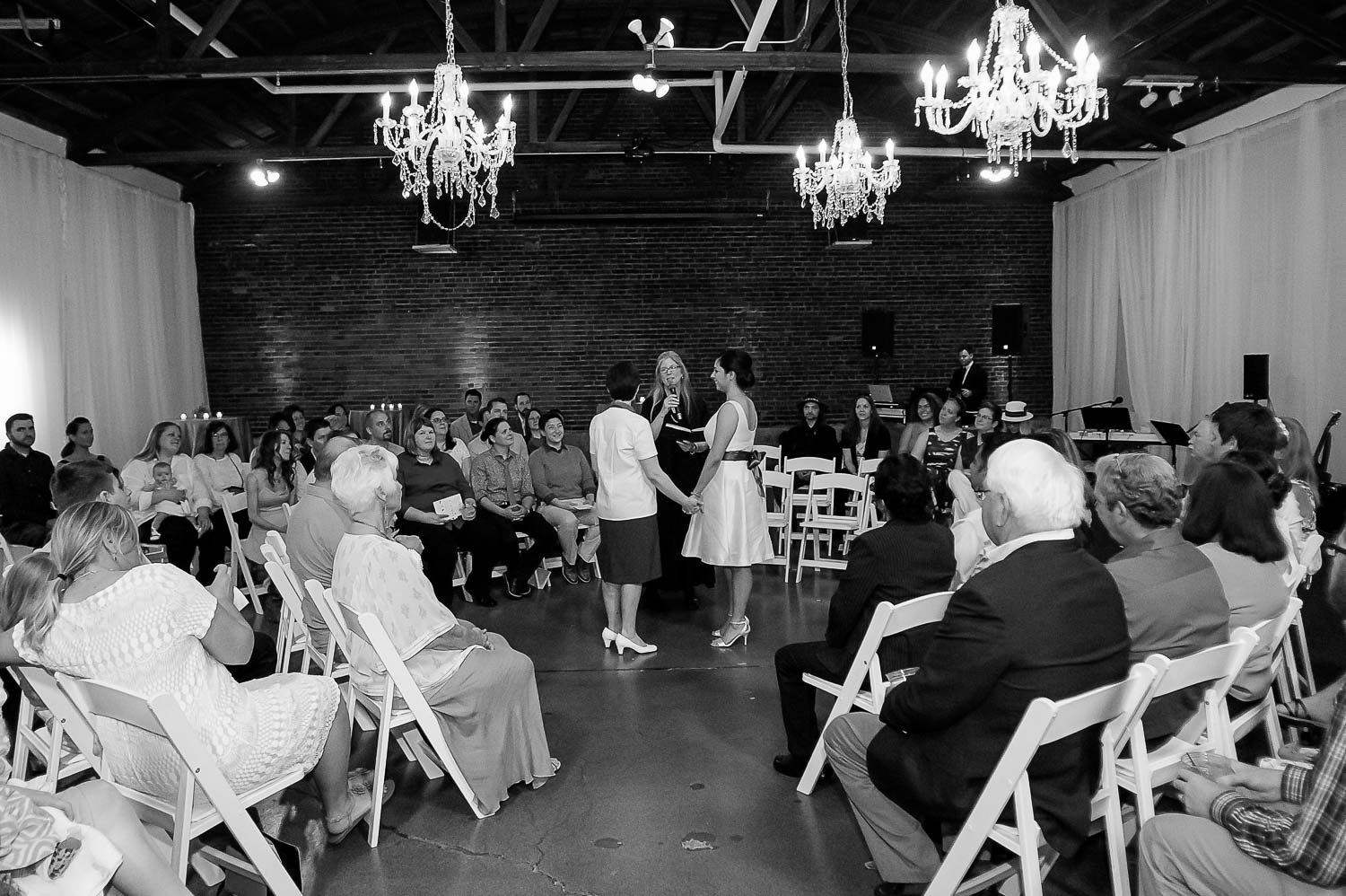 same sex couple holding hands during their wedding ceremony with a circular set up at Neu Neu in Minneapolis
