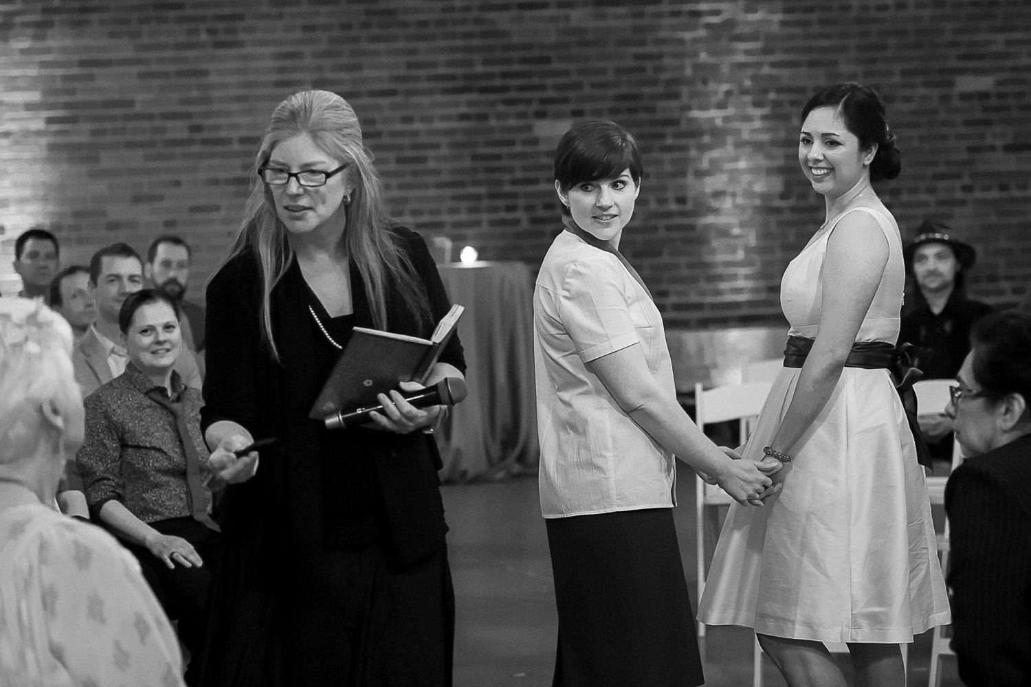 officiant talking to guests about blessing the wedding ring with the brides looking at everyone during their ceremony at Neu Neu in Minneapolis