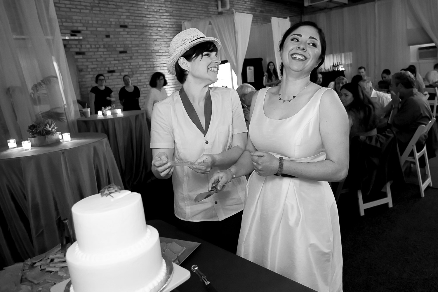 same sex couple cutting their wedding cake and laughing during the wedding reception in Minneapolis