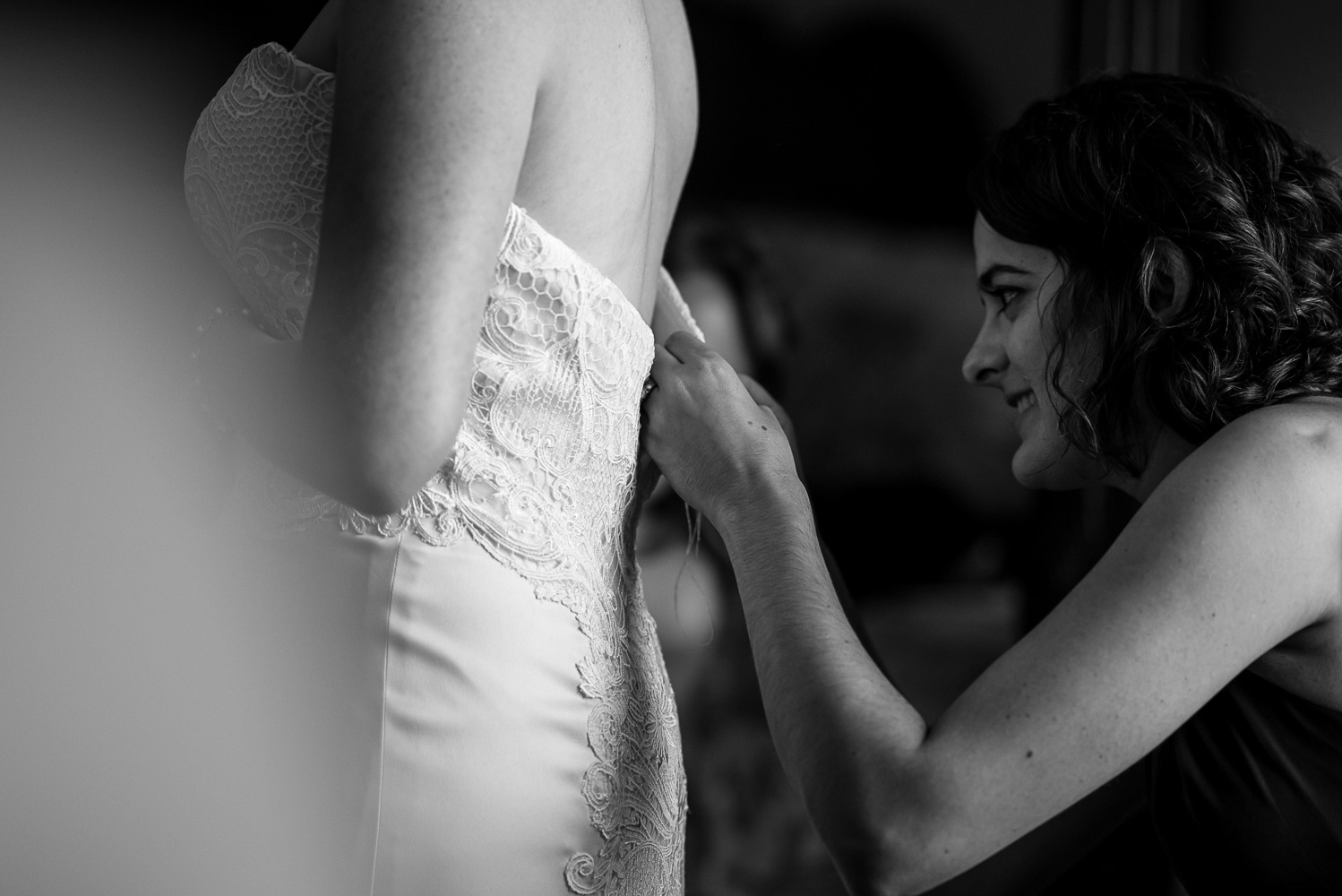bridesmaid buttoning the dress for the bride