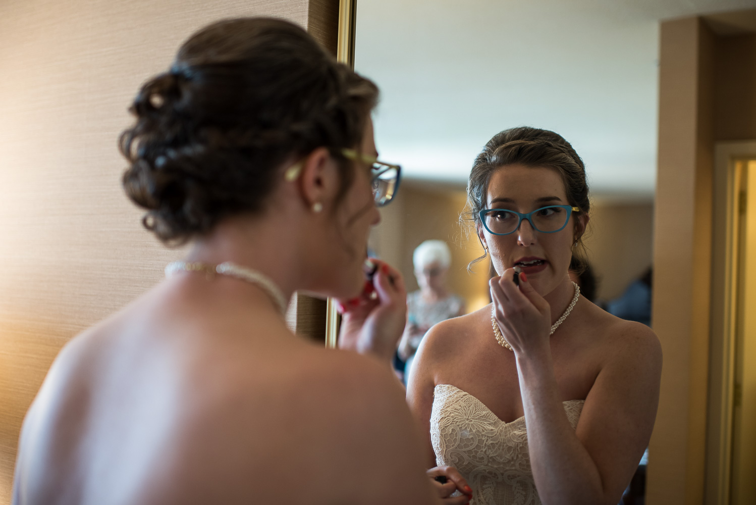 bride putting on makeup in front of the mirror