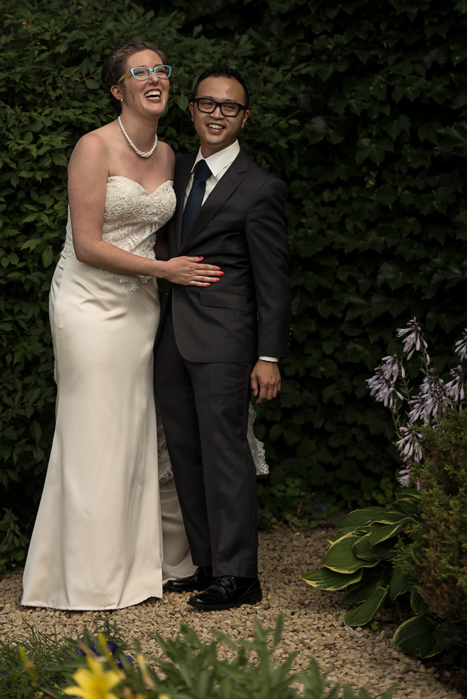 bride and groom laughing together in the garden in front of the St Paul hotel