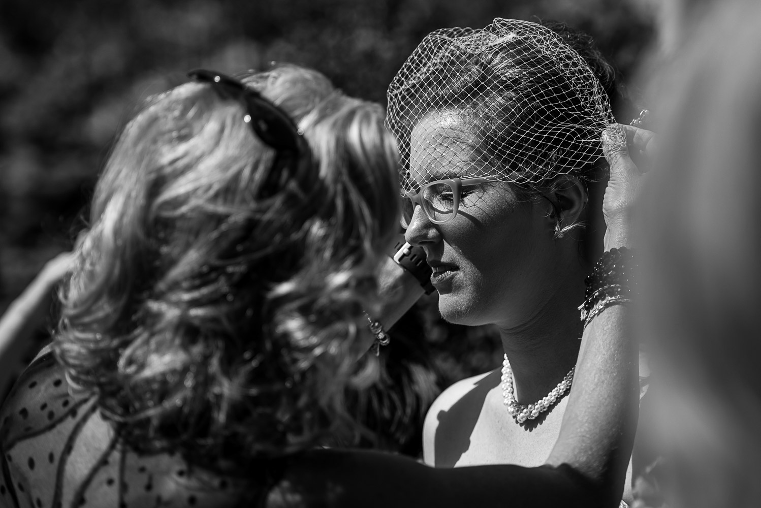 mom putting a birdcage veil on the bride