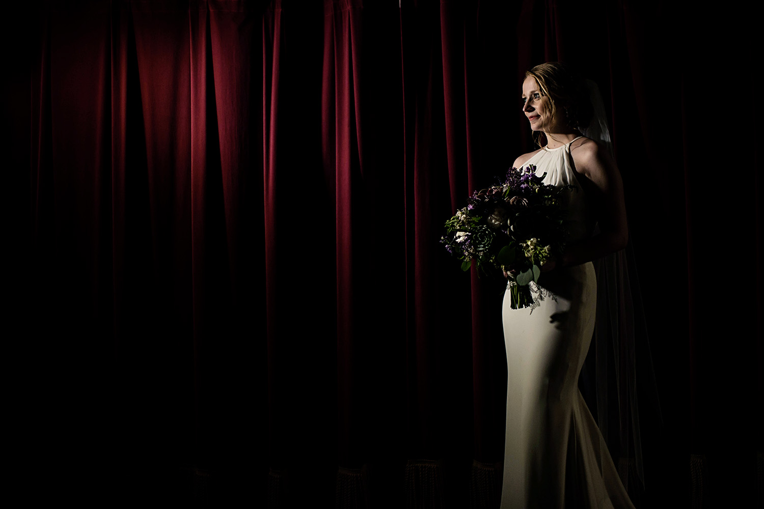 bride in front of a red curtain her flowers