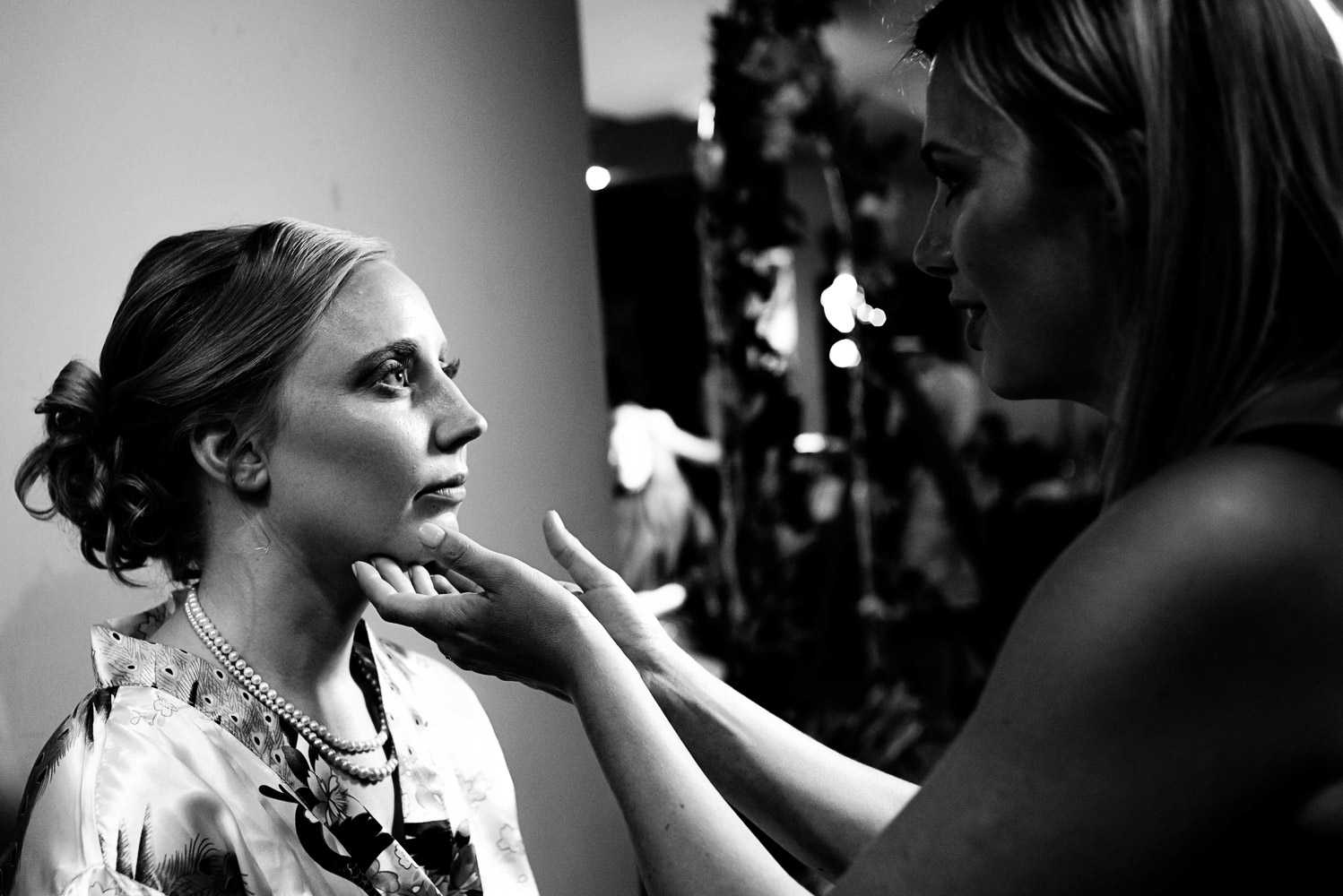 makeup artist putting on the finishing touches to the bride's makeup on her wedding day