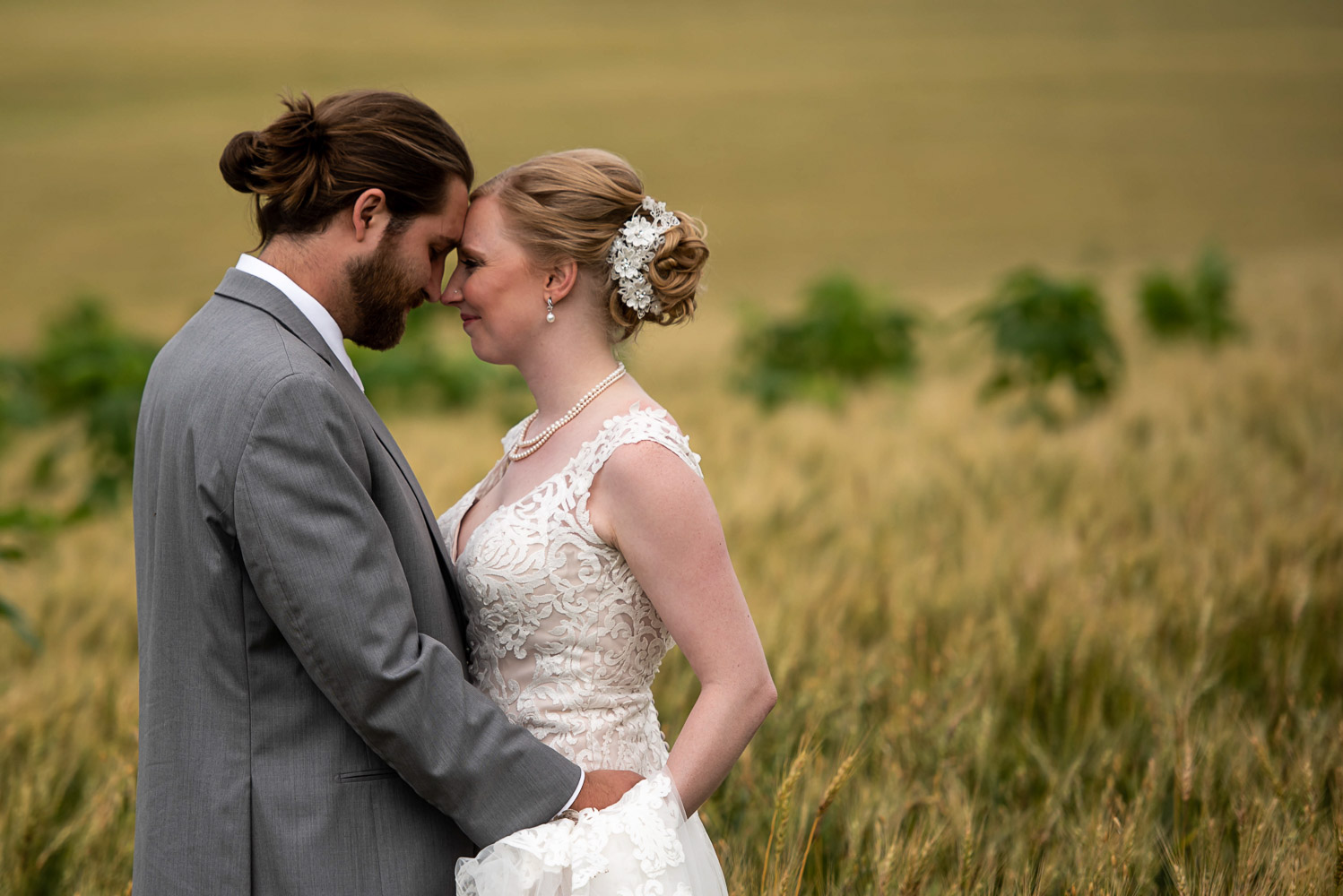 bride and groom in a field of yellow grass before their backyard summer wedding