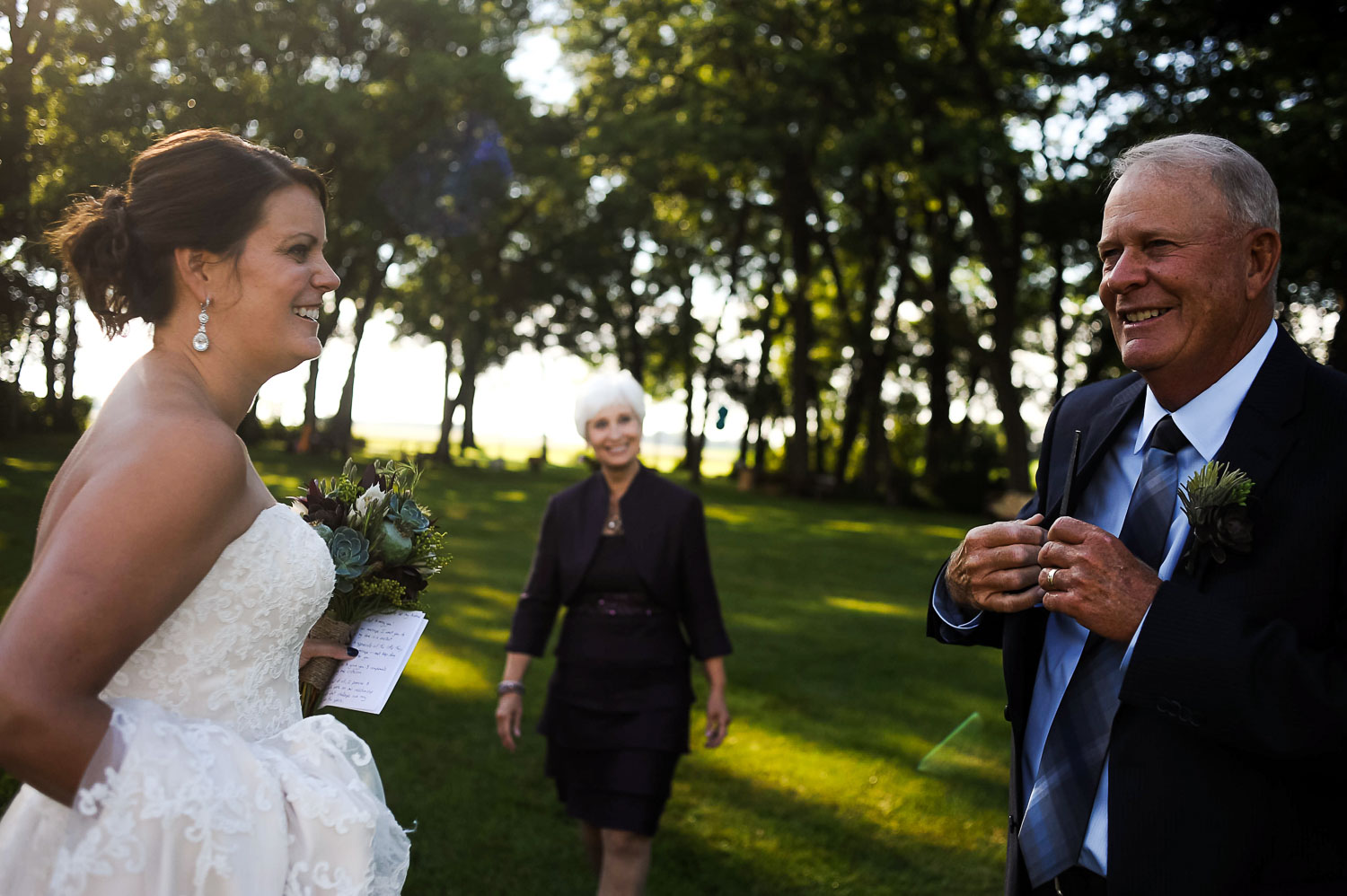 bride and her parents getting ready to walk down the aisle of her Iowa Farm wedding