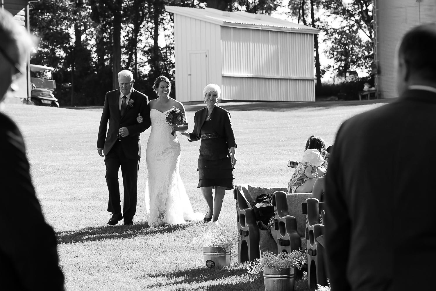 bride walking down the aisle with her mom and dad on their Iowa Farm