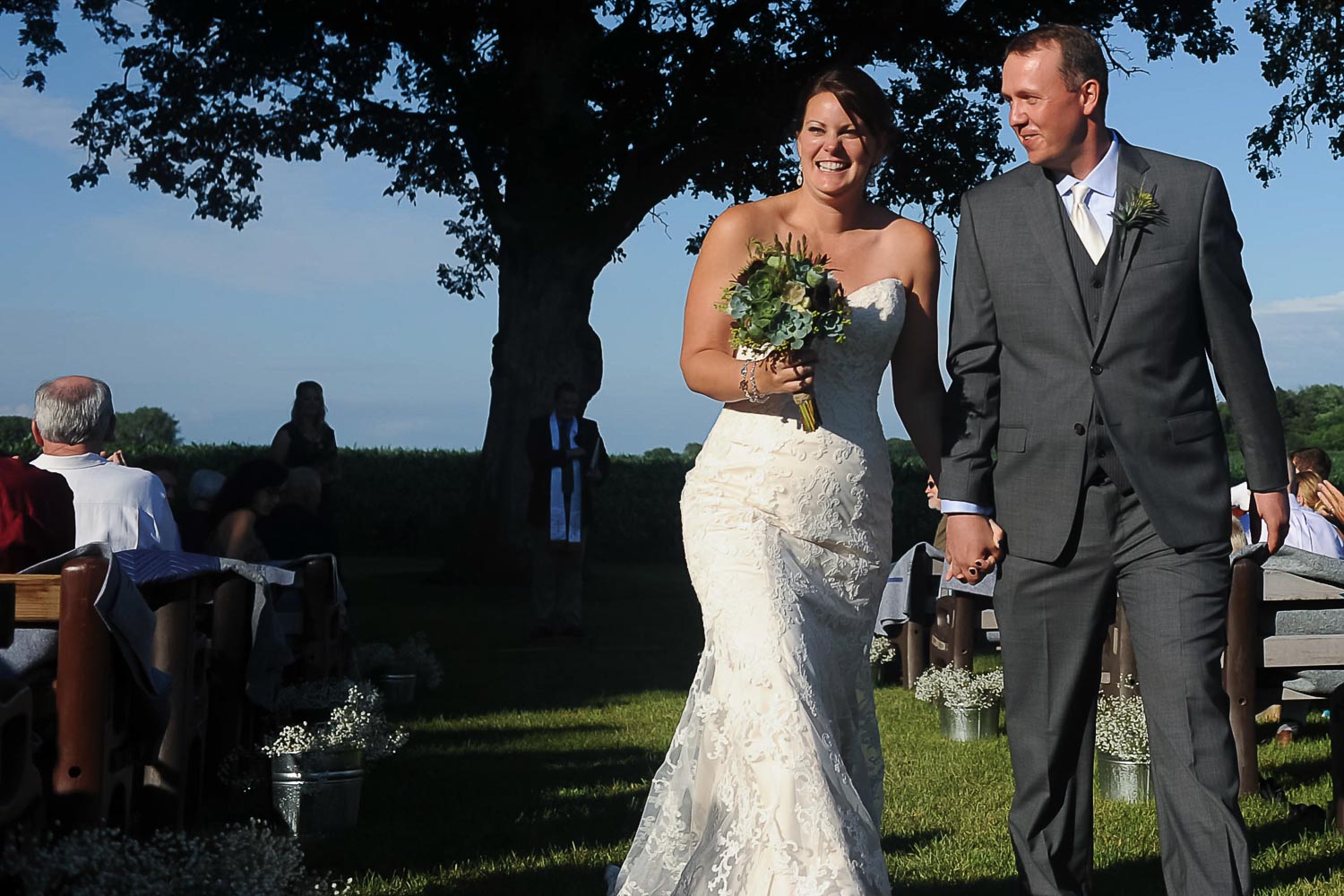 bride and groom walking during the recession of their Iowa farm wedding