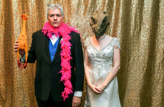 bride and groom using dinosaur props in a photo booth at their St Paul Science Museum wedding