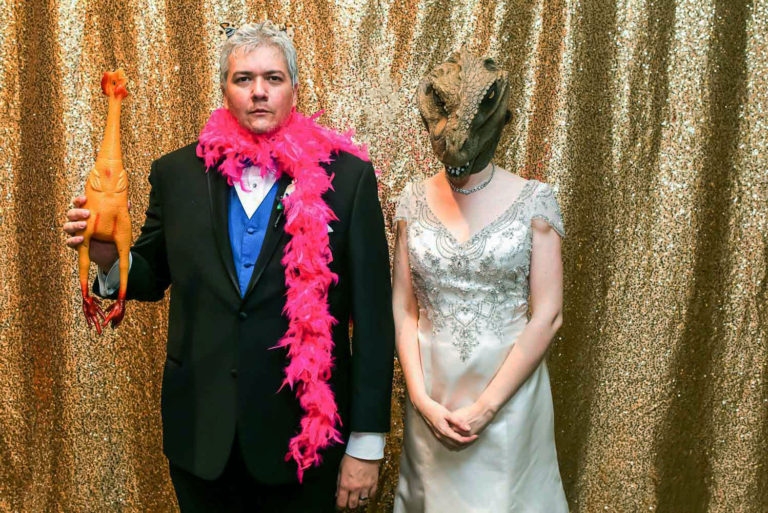 bride and groom using dinosaur props in a photo booth at their St Paul Science Museum wedding