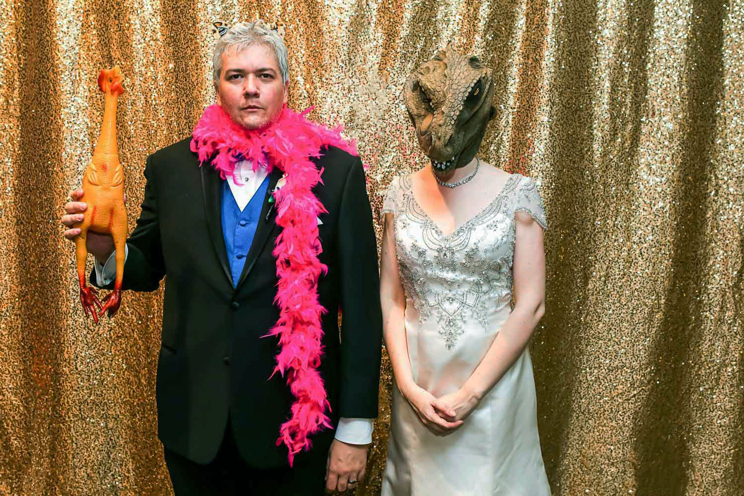 bride and groom using dinosaur props in a photo booth at their St Paul Science Museum wedding
