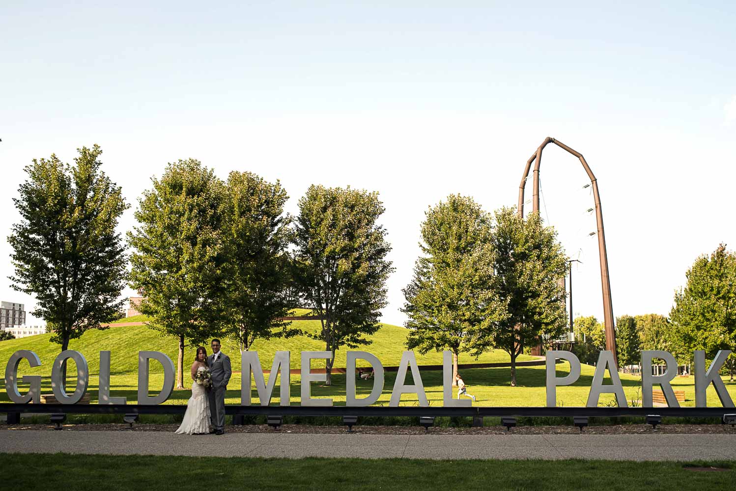bride and groom in front of the Gold Medal Park sign in Minneapolis
