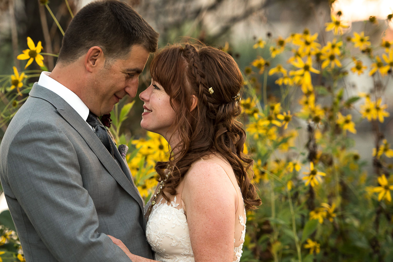 bride and groom touching foreheads by yellow flowers in Minneapolis
