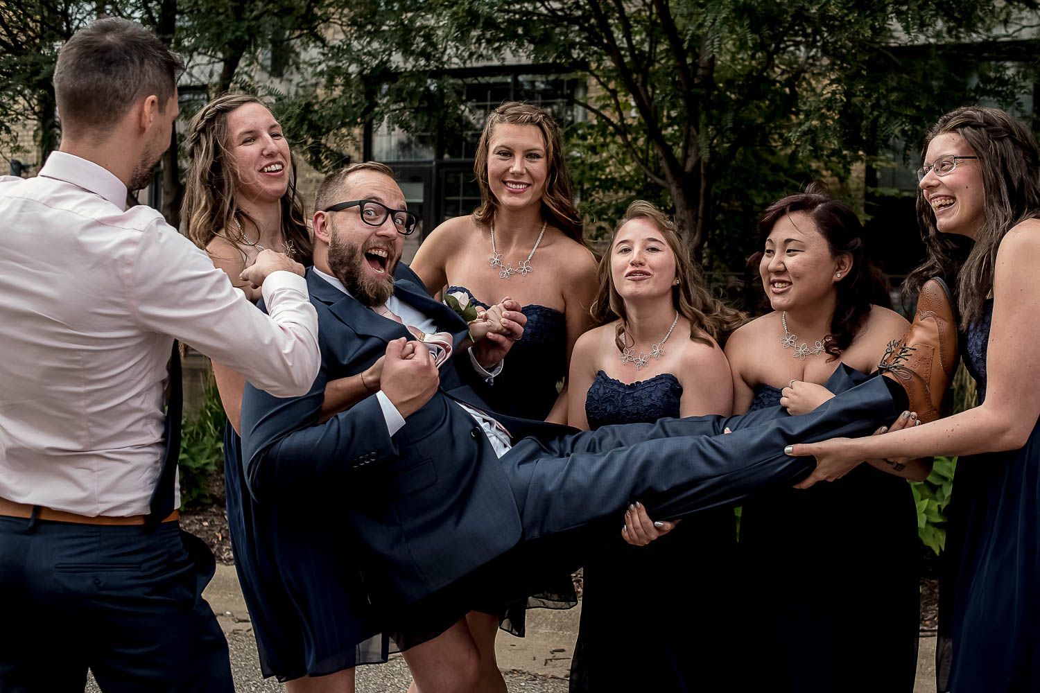 groom being held by the bridesmaids