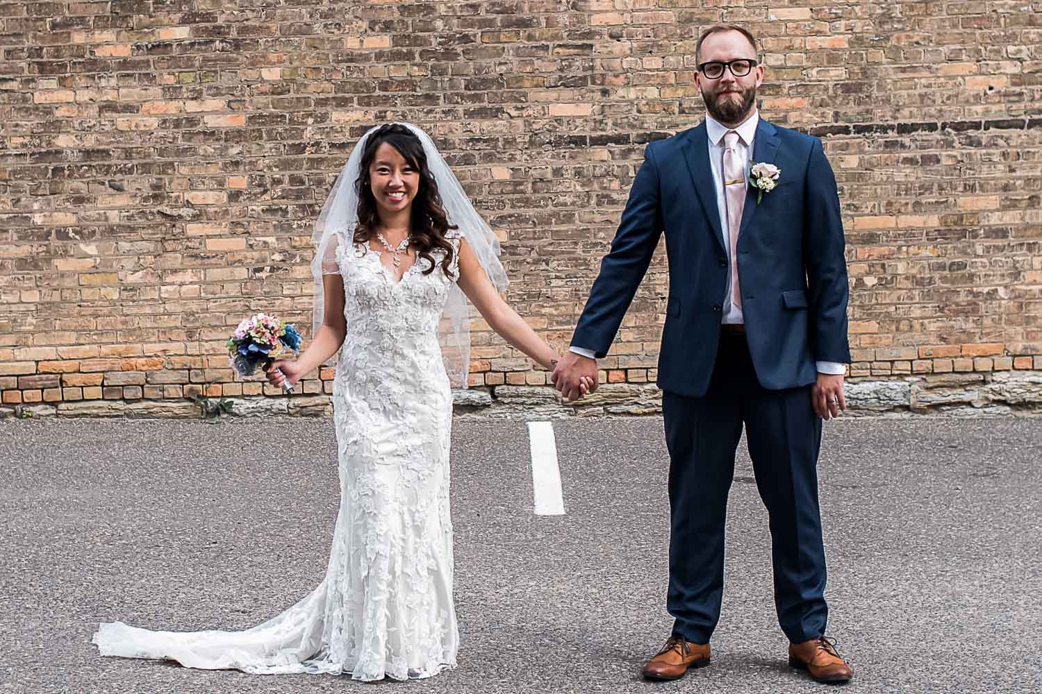 bride and groom holding hands next to a brick wall in the North Loop of Minneapolis