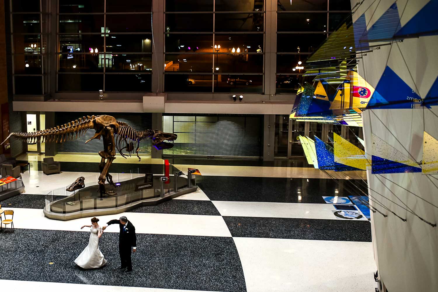 bride and groom dancing next to the t-rex at the Science Museum