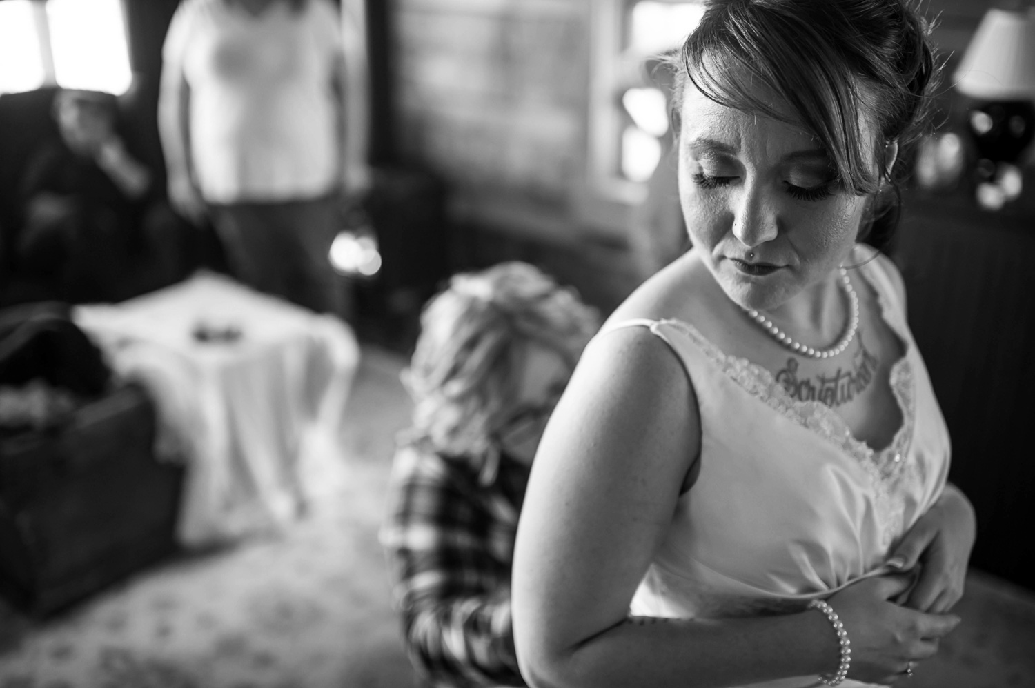 mom helping the bride put on her dress for her winter wedding in Minnesota