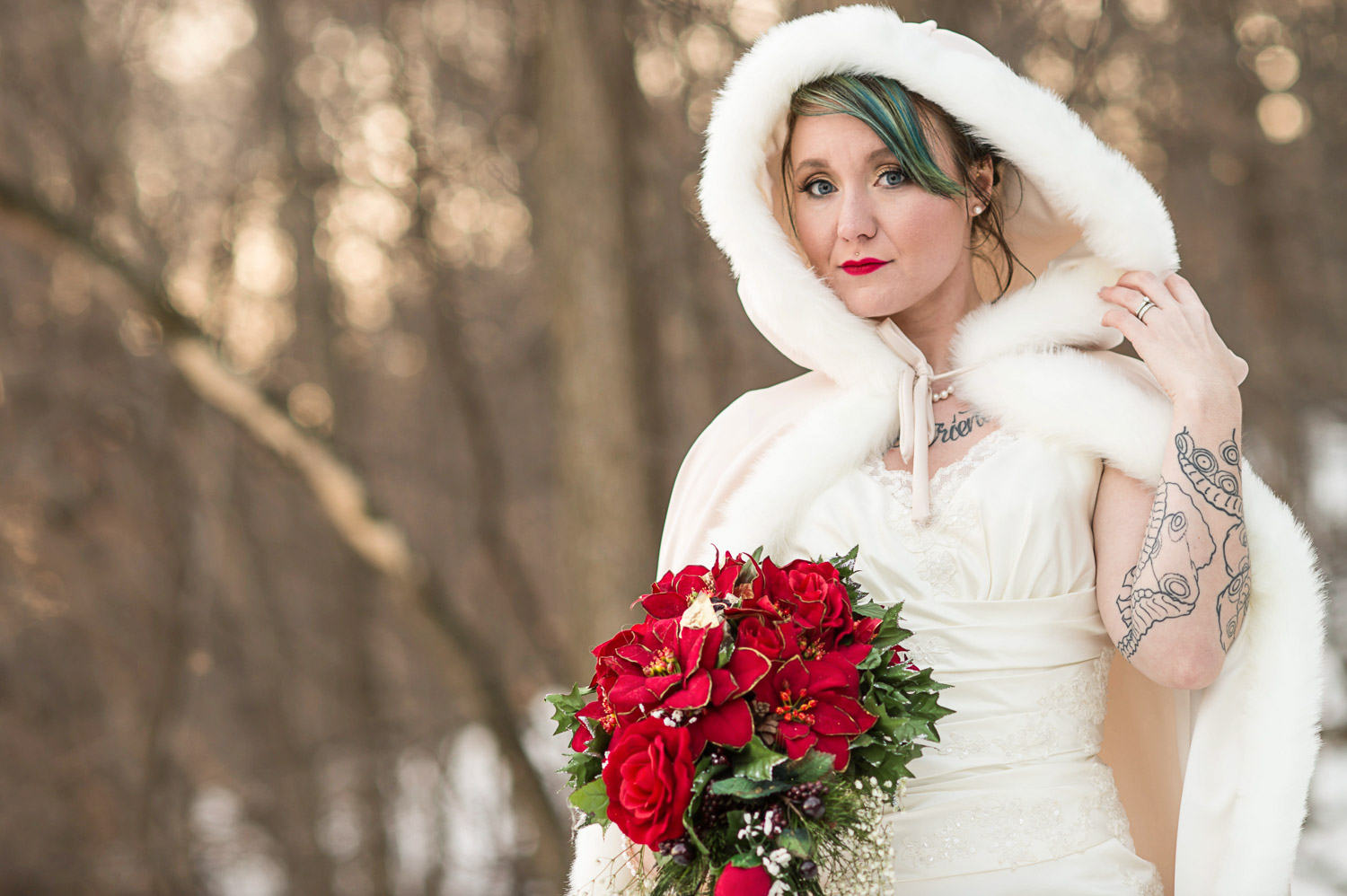 bride with green hair and red lipstick wearing a white fur lined cloak holding a red bouquet for her winter Minnesota wedding