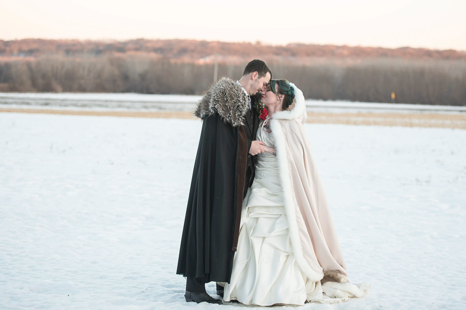 bride and groom wearing cloaks in the snow for their winter wedding in Minnesota