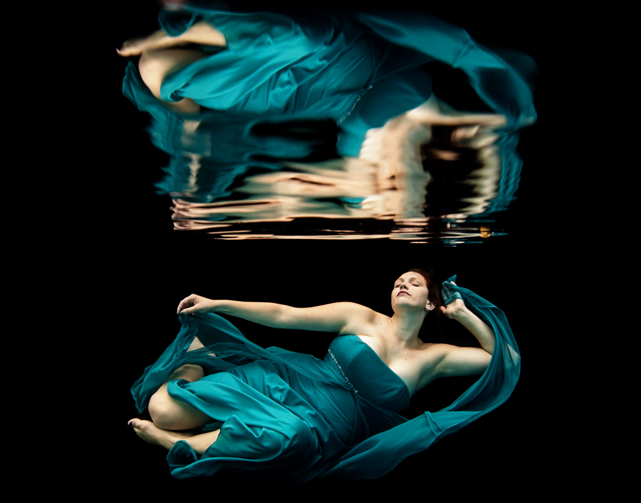woman underwater wearing a teal dress 