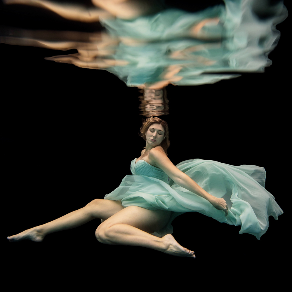 pregnant woman in a light green dress underwater maternity