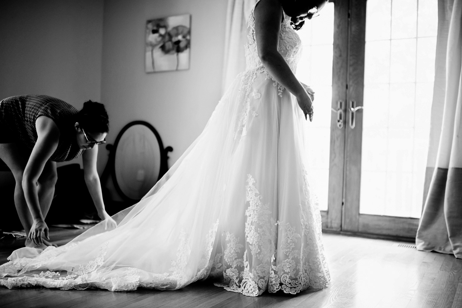bridesmaid fixing the brides dress 