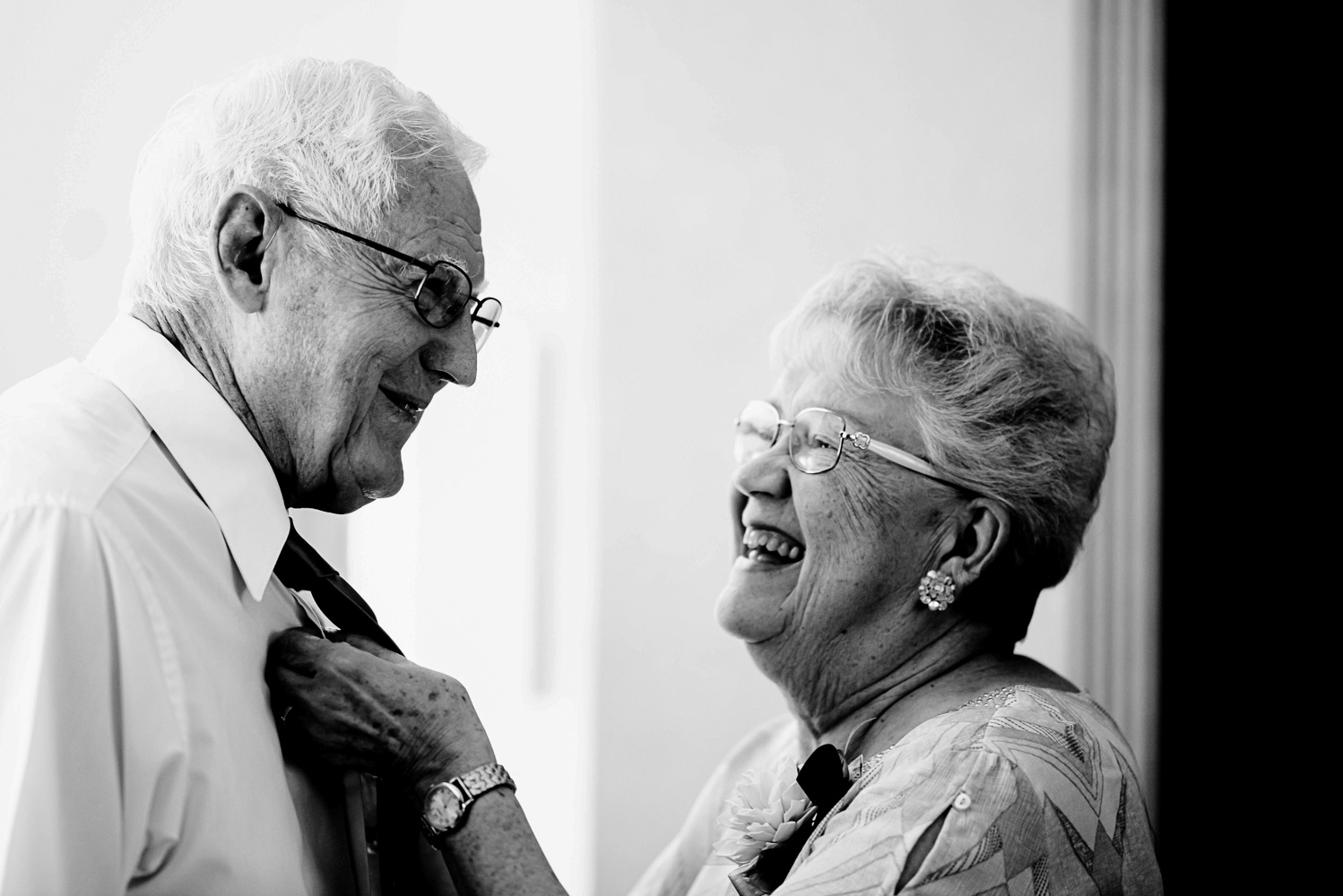 grandma pinning on the boutonniere on grandpa at before the ceremony at a summer wedding in Minnesota