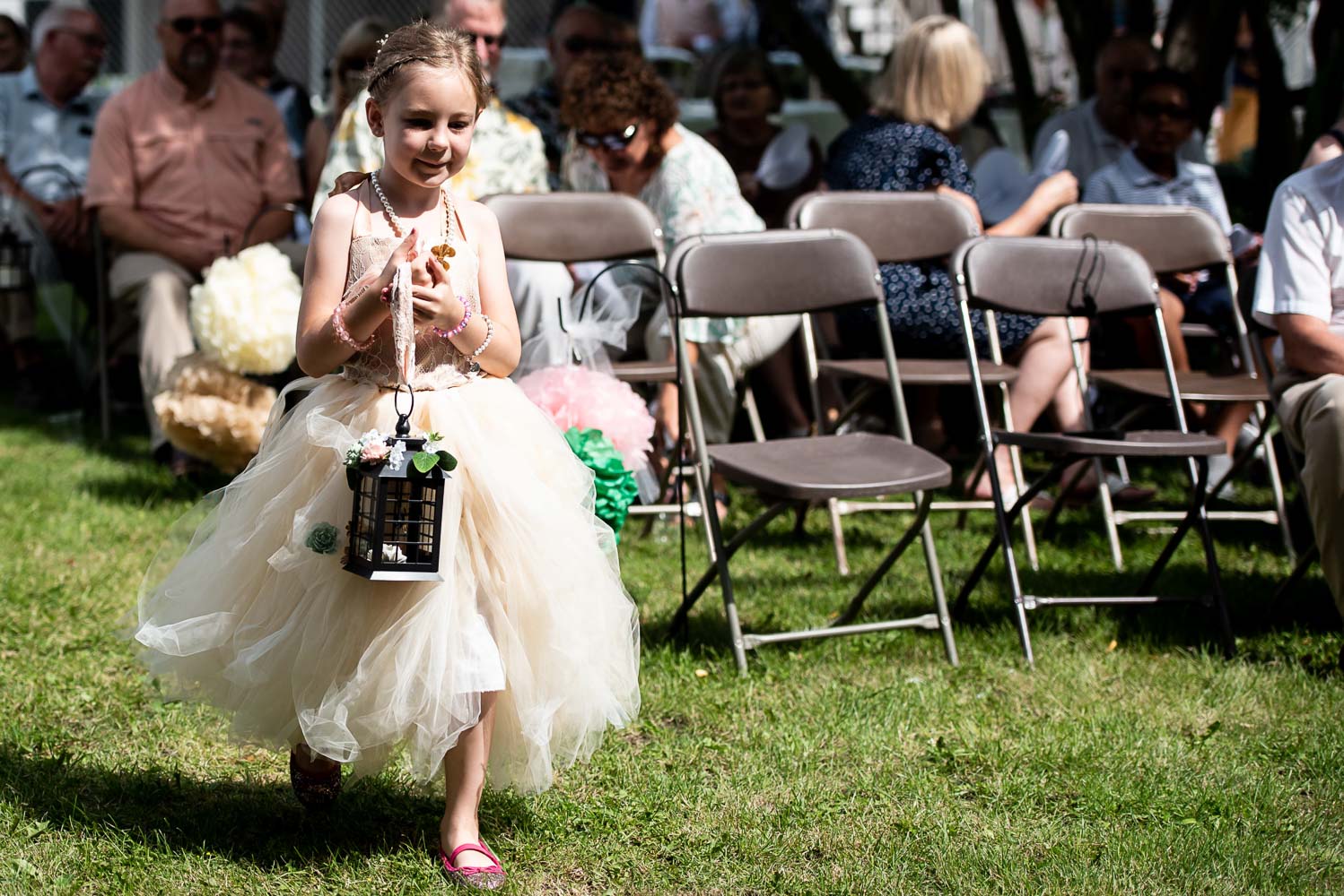 flower girl walking down the aisle before the summer wedding at the bride and groom's home in Minnesota