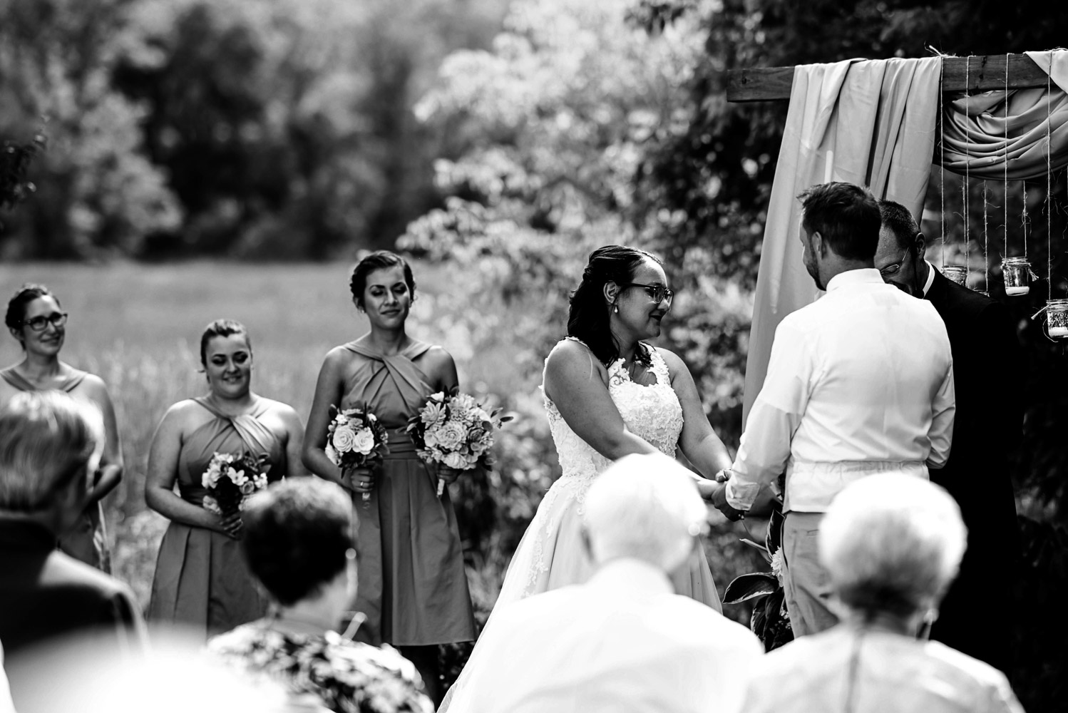 bride and groom holding hands during their ceremony at their summer wedding at their home