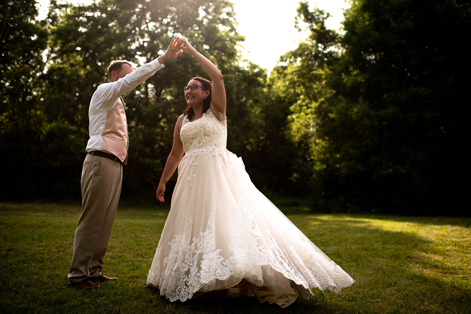 groom holding hands with the bride while she twirls and laughs 