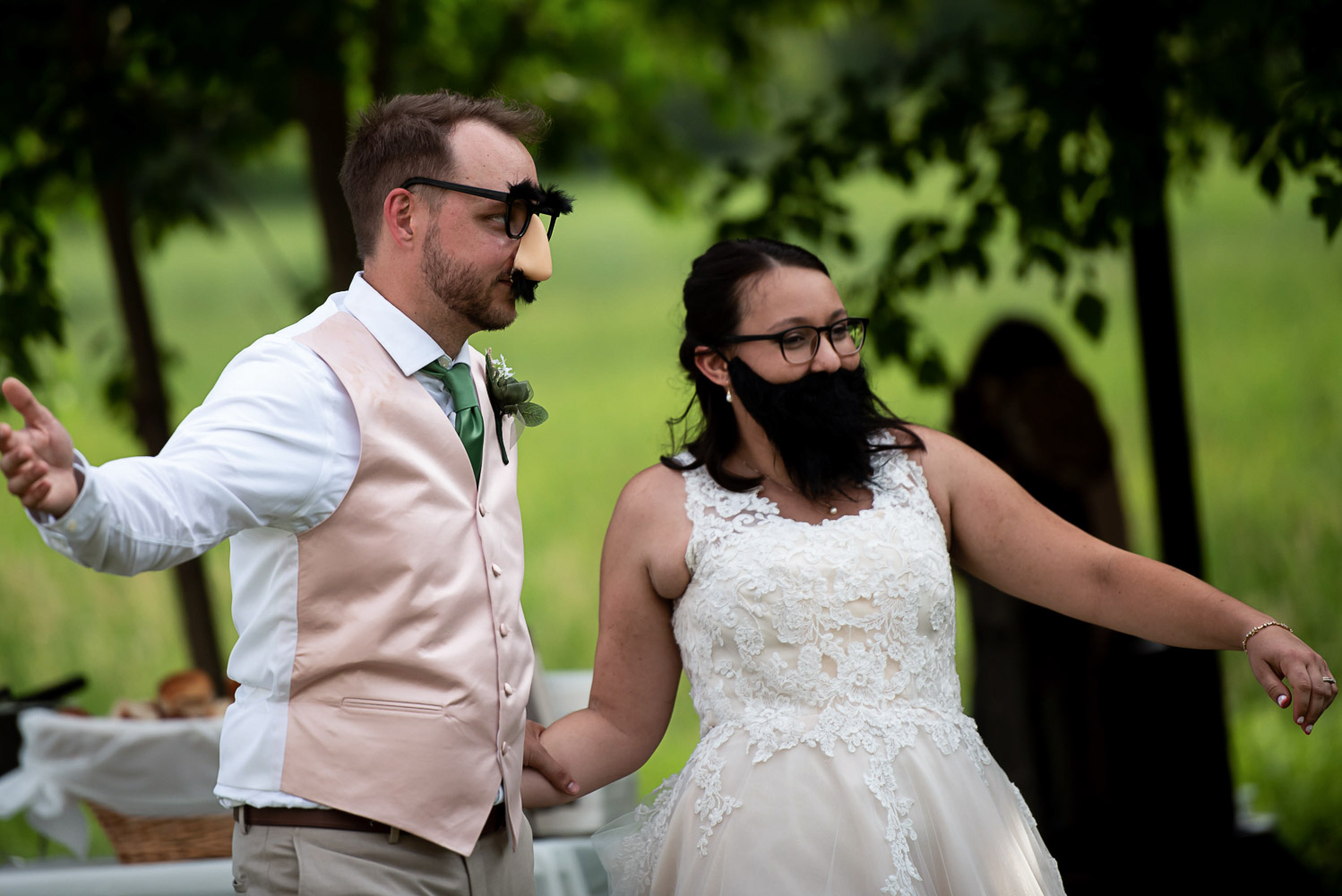 bride and groom with fake beard and glasses walking into their reception during their summer wedding at home