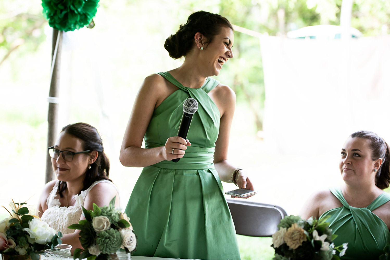 maid of honor wearing a green bridesmaid dress giving a speech during the wedding reception at the bride's home in Minnesota